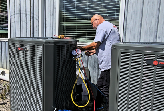 Technician checking an outdoor HVAC condenser unit